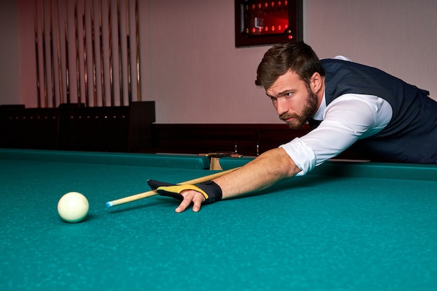 Homem segurando o braço na mesa de bilhar, jogando sinuca ou se preparando  com o objetivo de atirar bolas de bilhar. jogo de esporte sinuca bilhar