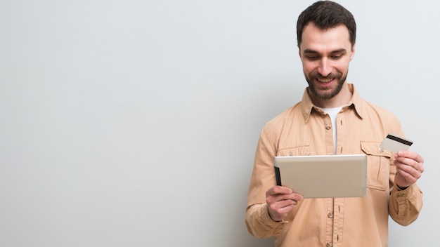 Homem segurando o cartão de crédito e tablet com espaço de cópia