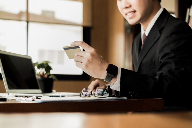 homem segurando o cartão de crédito e usando o site de compras de laptop e smartphone on-line