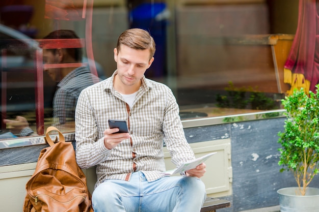 Homem segurando o celular ao ar livre na rua. homem usando smartphone móvel.