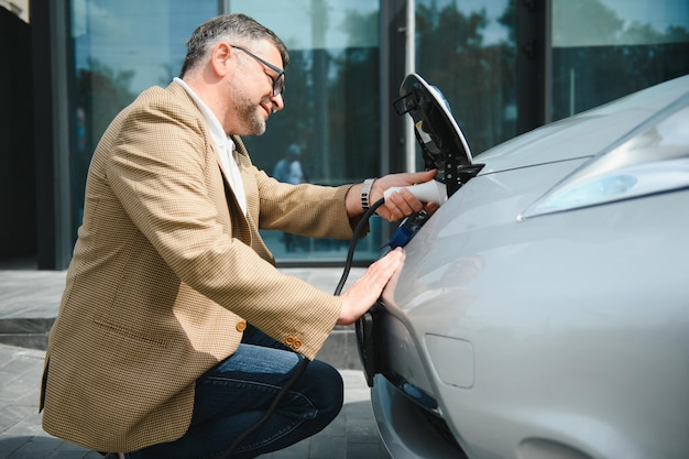 Homem segurando o conector de alimentação para carro elétrico