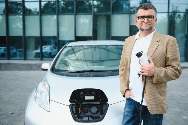 Homem segurando o conector de alimentação para carro elétrico