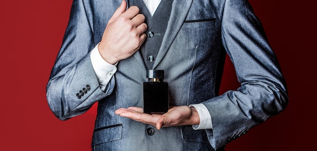 Foto homem segurando o frasco de perfume perfume masculino na mão no fundo do terno cheiro de fragrância