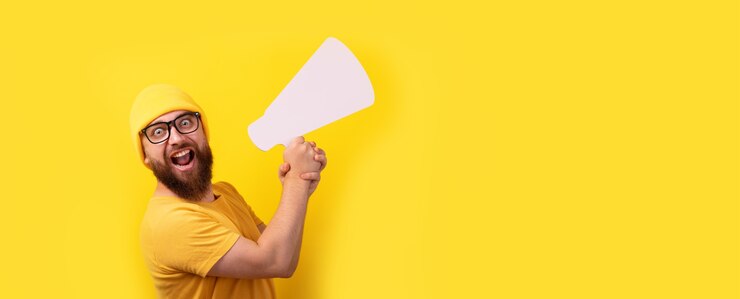 Foto homem segurando o megafone sobre fundo amarelo, layout panorâmico com espaço para texto