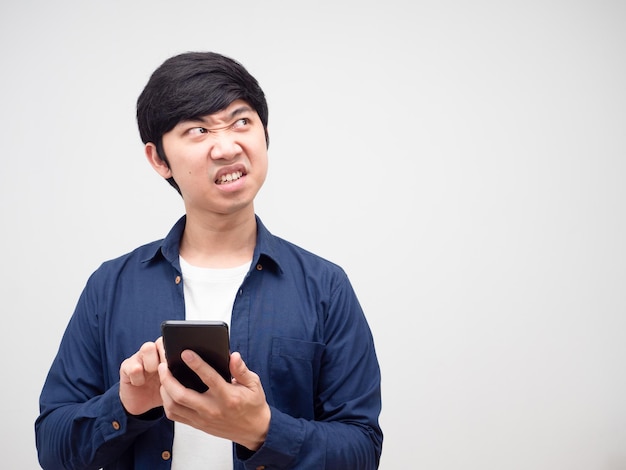 Homem segurando o telefone celular, sentindo raiva, olhando para o fundo do espaço da cópia branco isolado