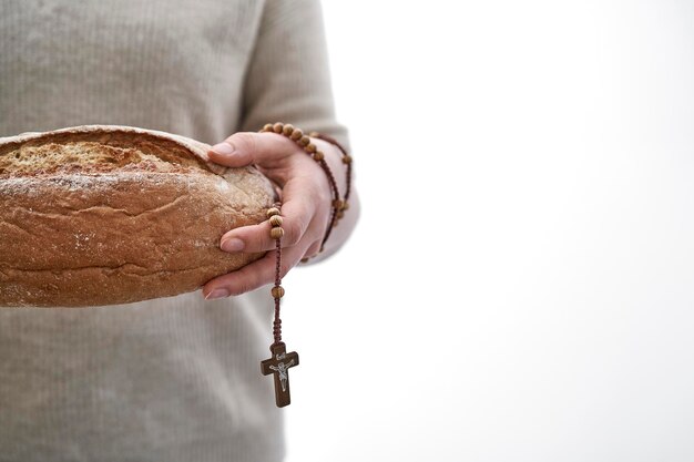 Foto homem segurando pão e rosário na frente da câmera