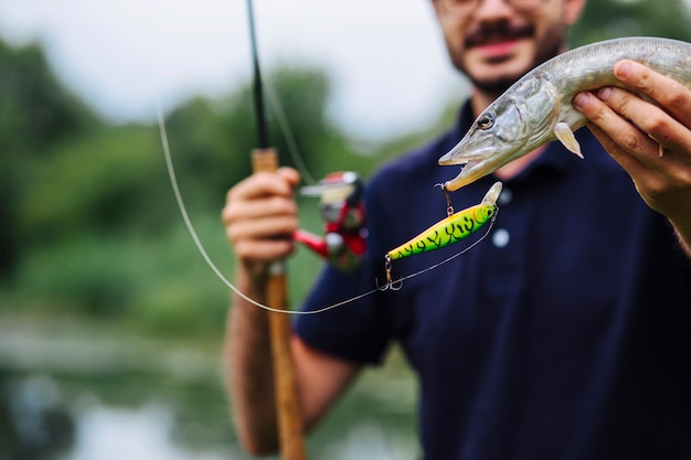 Homem, segurando, peixe, pegado, em, gancho pescando, com, isca