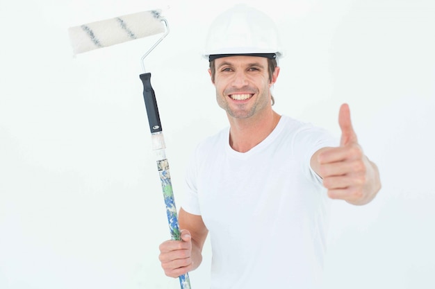 Homem segurando rolo de pintura enquanto gesticula polegares para cima