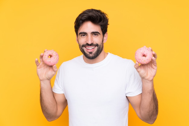 Homem segurando rosquinhas sobre parede amarela