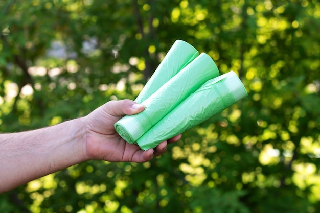 Homem segurando sacos plásticos ecológicos de lixo bio em rolos ao ar livre