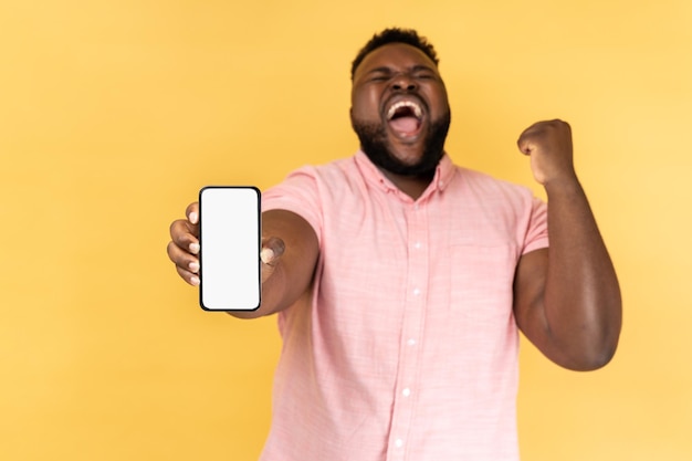 Homem segurando smartphone gritando fazendo sim gesto comemorando a vitória na loteria online