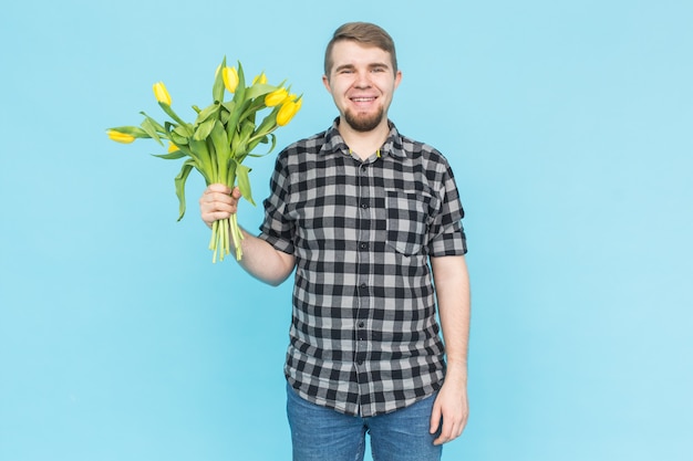 Homem segurando tulipas amarelas em azul