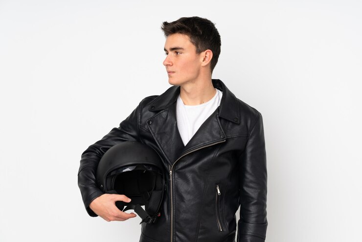 Foto homem segurando um capacete de moto isolado na parede branca, olhando de lado