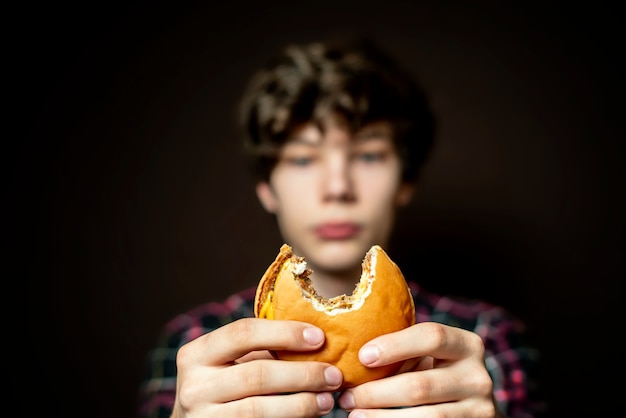 Homem segurando um cheeseburger mordido e comendo-o apaixonadamente f