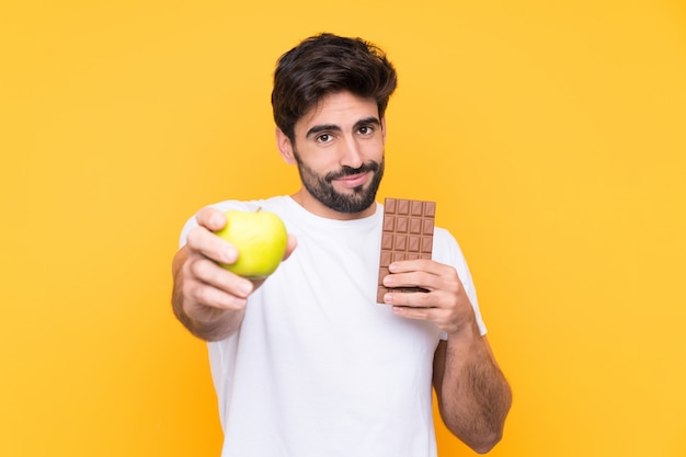 Homem segurando um chocolate e uma maçã