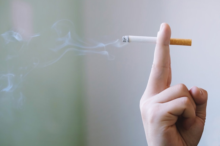 Foto homem segurando um cigarro na mão. a fumaça do cigarro se espalhou.