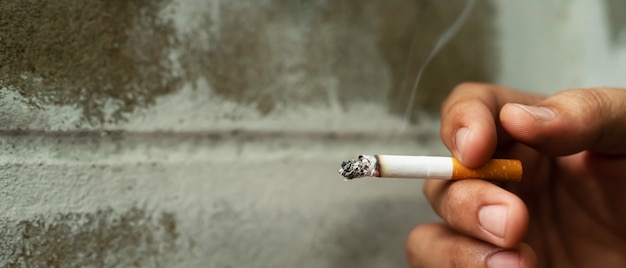 Foto homem segurando um cigarro na mão e fumando