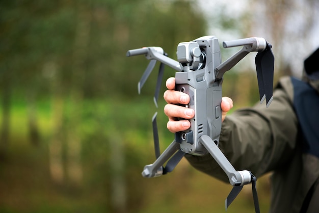 Homem segurando um drone com a mão antes de voar pelo céu