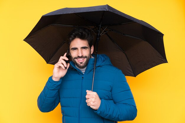 Homem segurando um guarda-chuva sobre parede amarela isolada