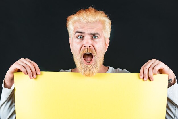 Homem segurando um outdoor em branco amarelo isolado no fundo preto