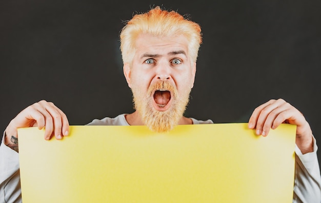 Homem segurando um outdoor em branco amarelo isolado no fundo preto