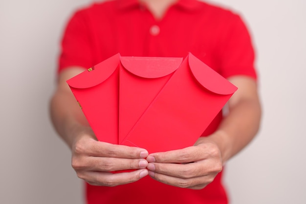 Homem segurando um presente de dinheiro de envelope vermelho chinês para feliz feriado do Ano Novo Lunar