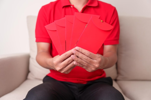 Homem segurando um presente de dinheiro de envelope vermelho chinês para feliz feriado do Ano Novo Lunar