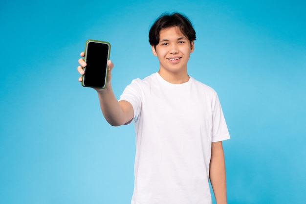 Homem segurando um smartphone com um fundo azul de tela em branco