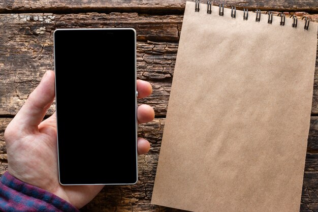 Foto homem segurando um smartphone perto de notebook