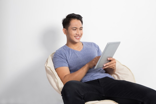 Homem segurando um tablet enquanto está sentado na cadeira