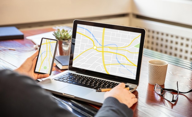 Foto homem segurando um telefone celular e trabalhando com um mapa de computador no plano de negócios do escritório de telas