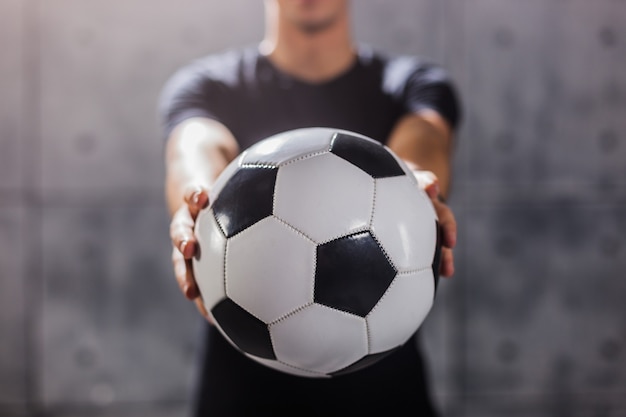 Homem segurando uma bola de futebol nas mãos