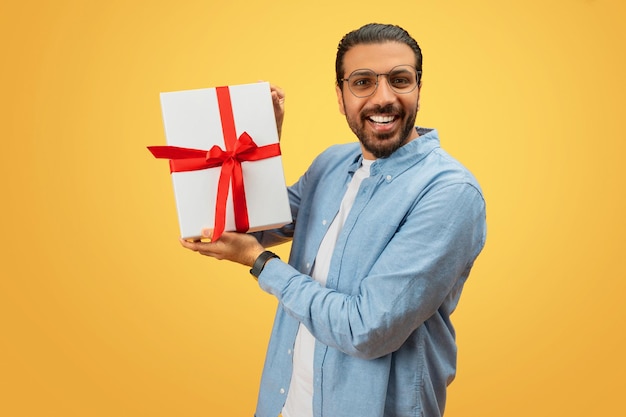 Homem segurando uma caixa de presentes em direção à câmera