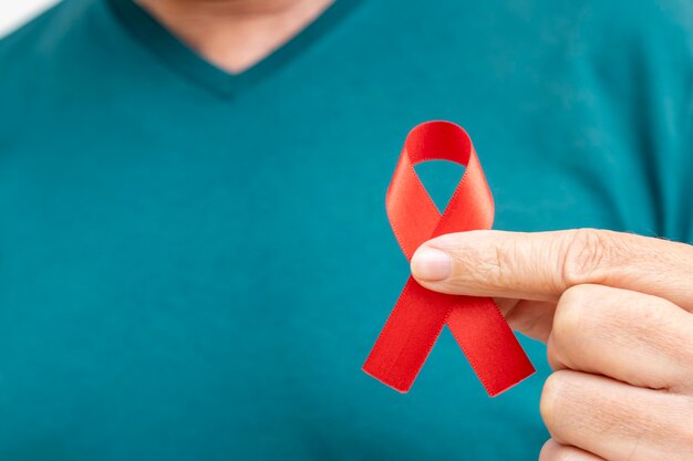 Homem segurando uma fita vermelha de conscientização sobre a AIDS / SIDA conceito de prevenção do Dia Mundial da AIDS e do Dia Mundial da Diabetes