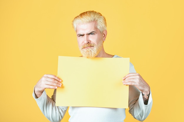 Homem segurando uma folha de papel em branco isolada em fundo amarelo