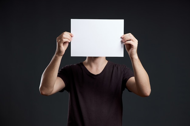 Homem segurando uma folha de papel vazia nas mãos