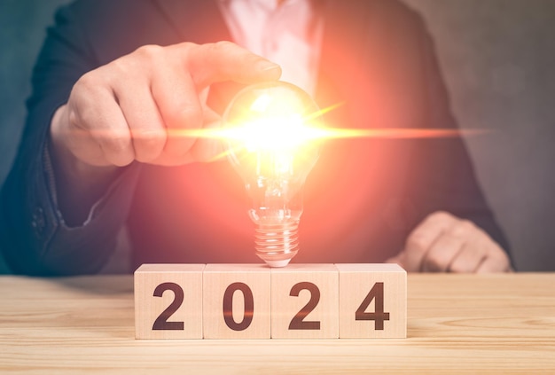 Homem segurando uma lâmpada de luz sobre o crescimento e investimento de ideias de negócios de 2024 Ano Novo Ideia de Negócio Pensamento Criativo Brainstorming Estratégia de Resolução de Objetivos Começo de Ano Novo Conceitos
