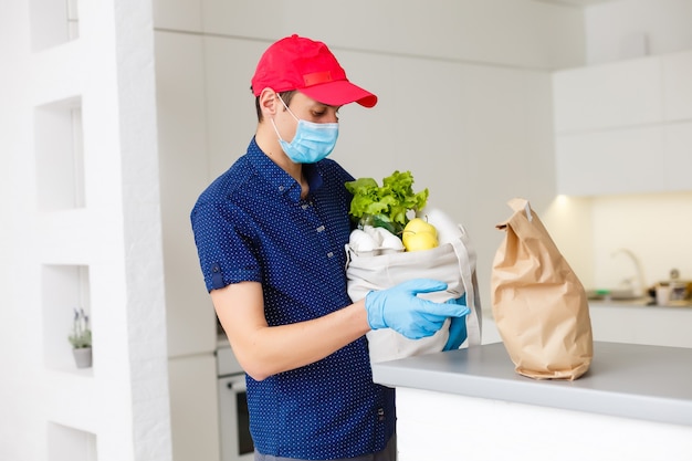 Homem segurando uma sacola cheia de diferentes alimentos saudáveis em uma mesa de madeira na cozinha de casa close-up