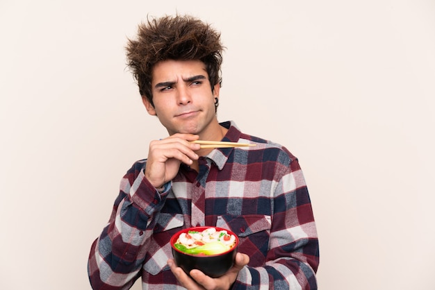 Homem segurando uma tigela cheia de macarrão