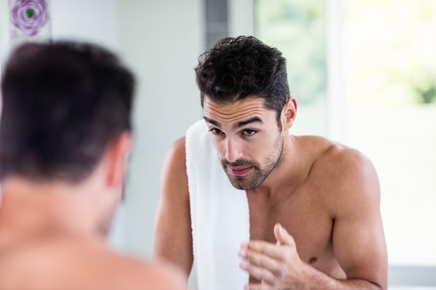 Homem sem camisa bonito, olhando no espelho no banheiro