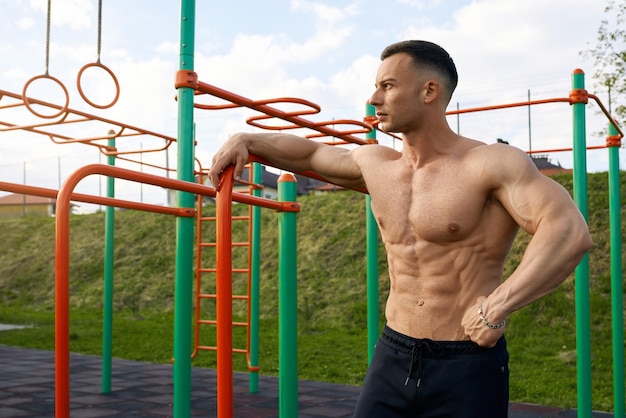 Homem sem camisa com torso musculoso em pé no campo esportivo