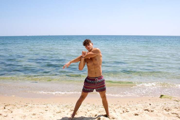 Foto homem sem camisa de pé na praia contra o céu