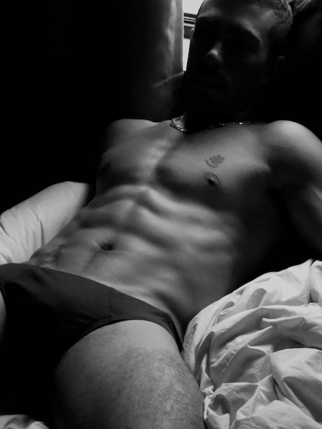 Foto homem sem camisa deitado na cama em casa