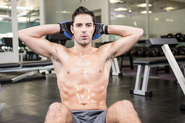 Homem sem camisa, fazendo sentar-se no ginásio