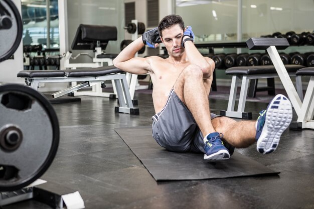 Homem sem camisa, fazendo sentar-se no ginásio