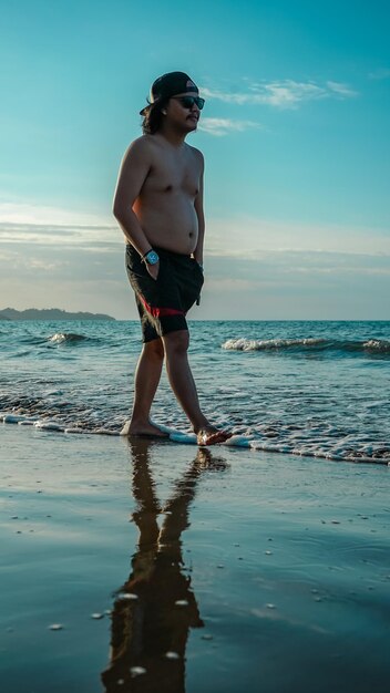 Foto homem sem camisa na praia.