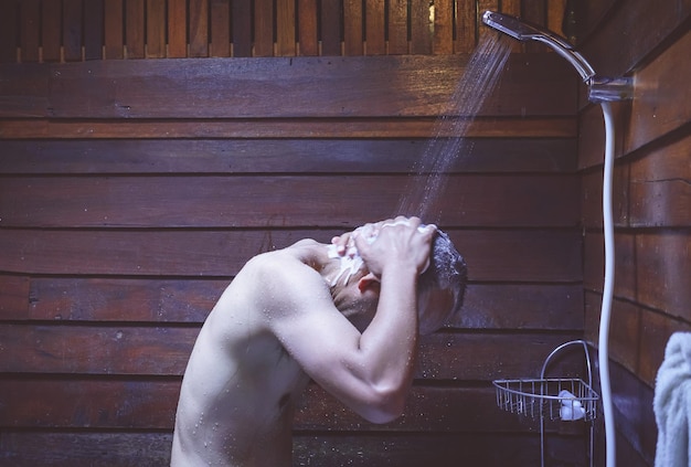 Homem sem camisa tomando banho na casa de banho