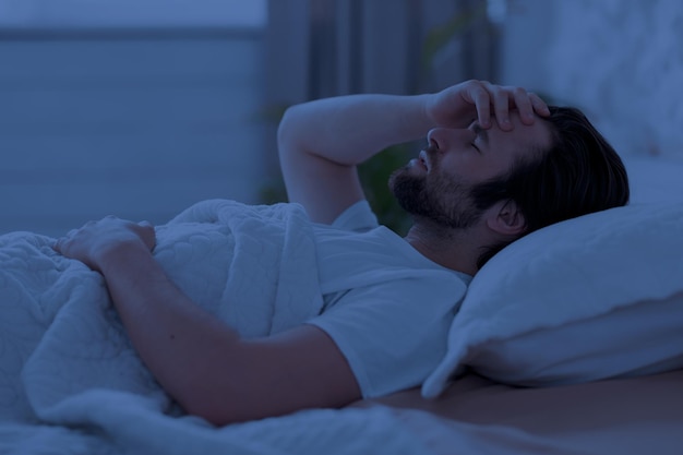 Homem sem dormir deitado na cama sozinho à noite