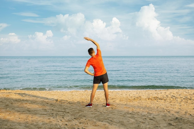 Homem sênior ativo fazendo exercícios de alongamento na praia Conceito de estilo de vida ativo