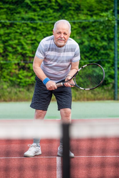 Homem sênior ativo jogando tênis na quadra, conceito de esporte, estilo de vida saudável